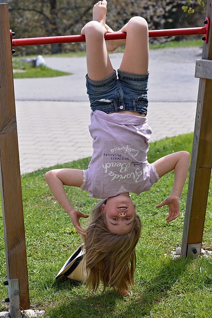 Mädchen hängt Kopf über von einer Reckstange